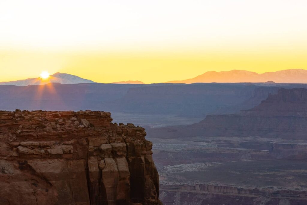 A sunset landscape in Canyonlands National Park in Southern Utah. The sky is yellow and the canyons turned purple.