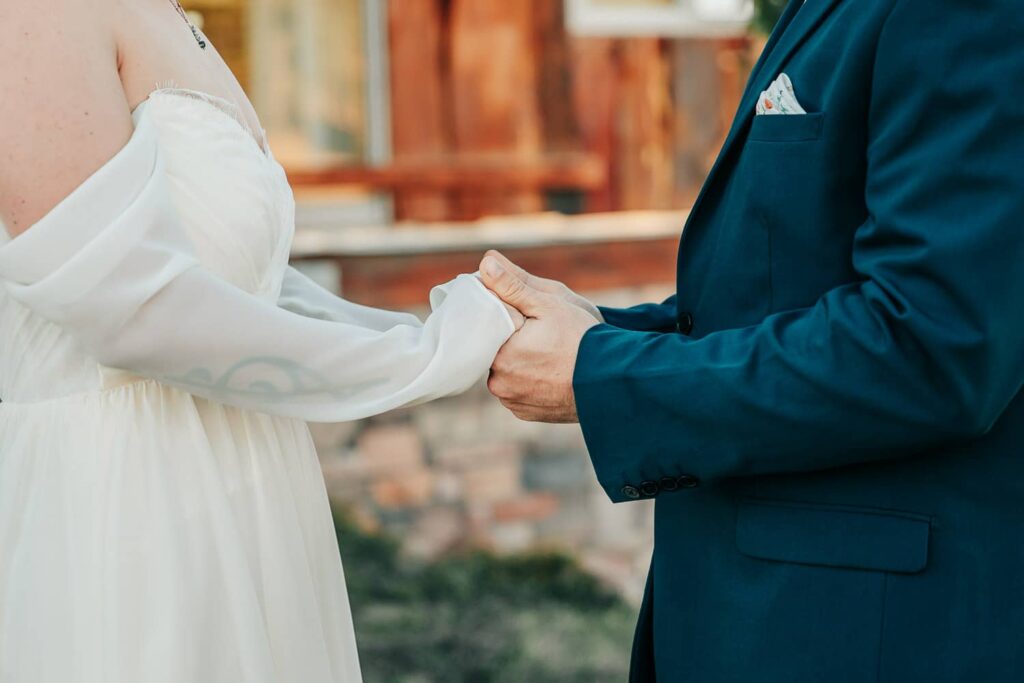 A close up of a wedding couple holding hands.