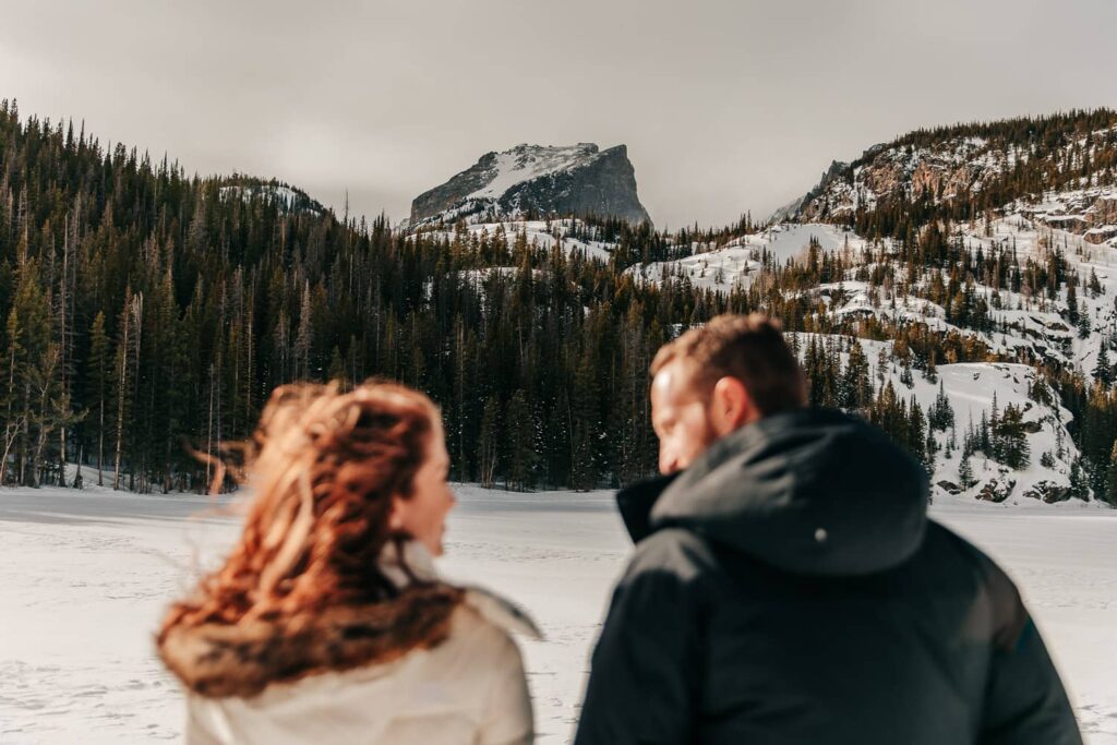 An eloping couple on their wedding day looking at each other. The focus is on the Colorado mountain peak behind them.