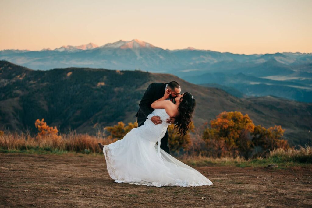 A couple in wedding attire during their colorado off-roading elopement. They couple is kissing while the groom dips the bride back.