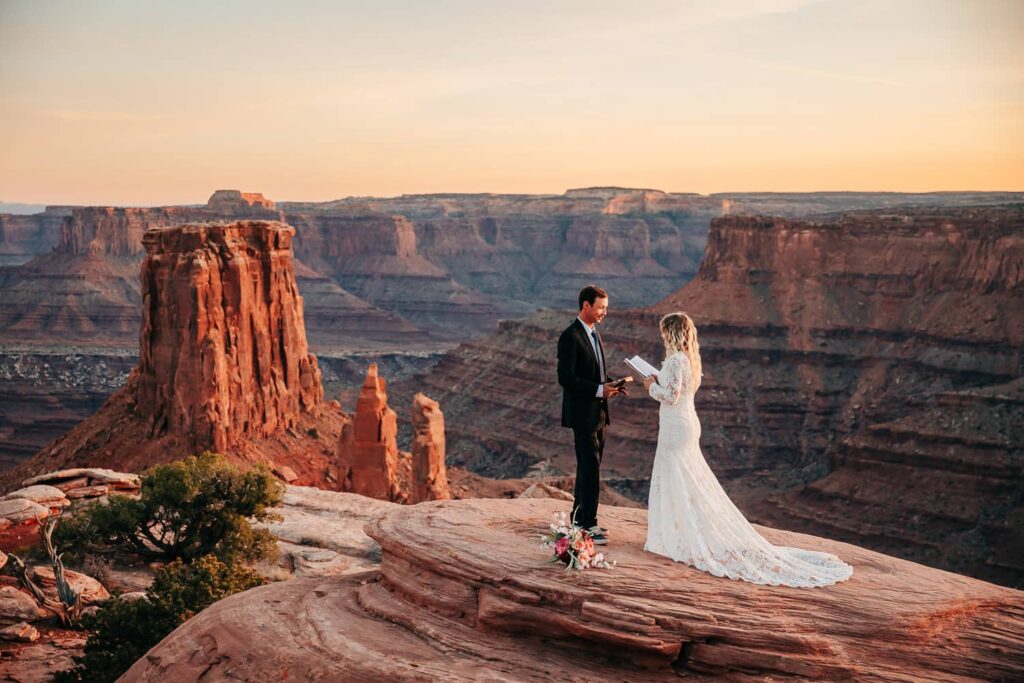 A couple sharing vows during their elopement in Moab, Utah. There is a large canyon behind them.