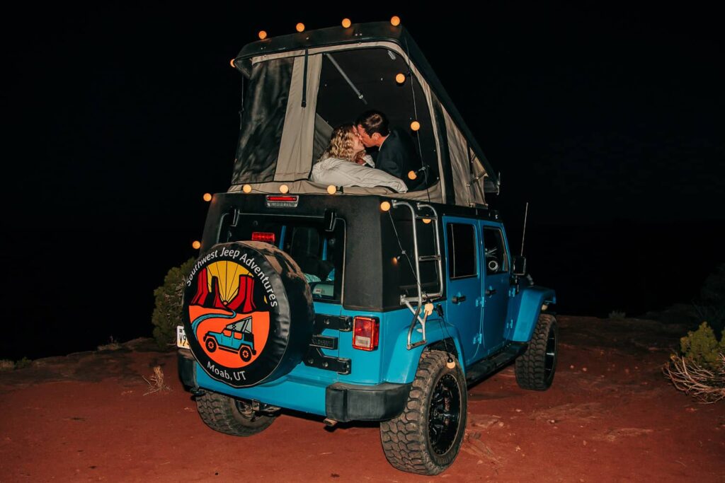 A couple during their Moab elopement, kissing in a camper jeep at night.