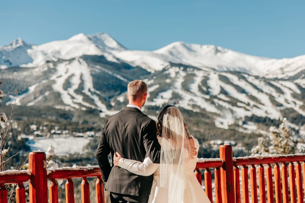 Couple in wedding attire looking off at mountains during their lodge at breckenridge wedding